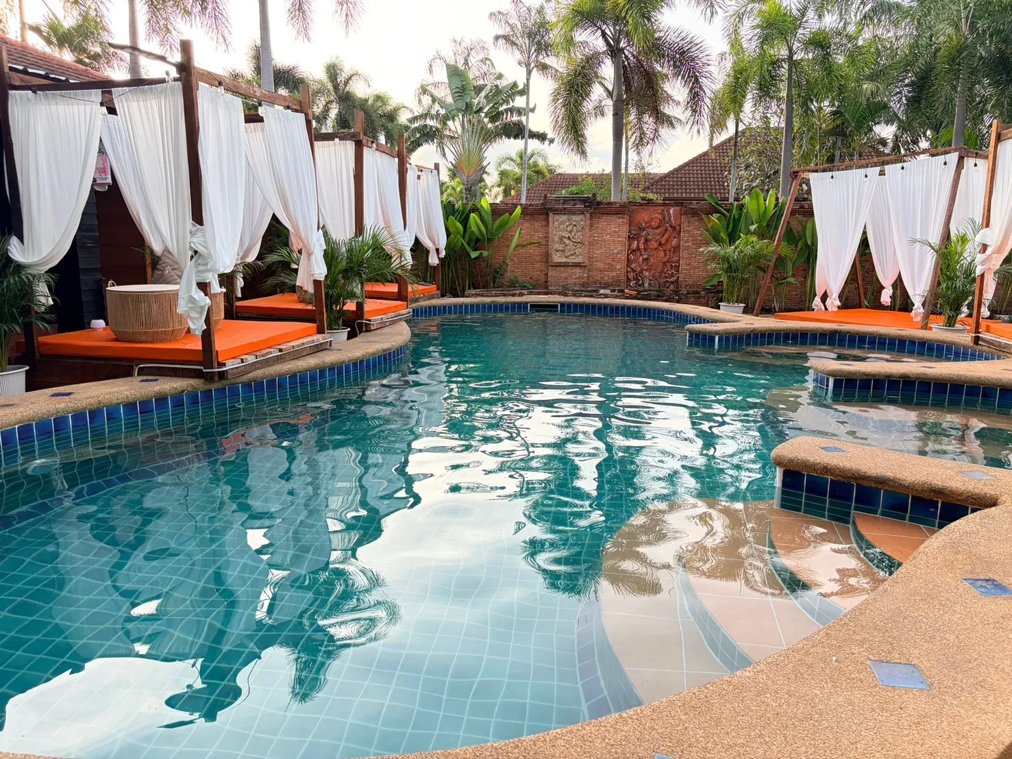 Outdoor pool with curtained daybeds at Dewata Wellness Sauna Pattaya at night