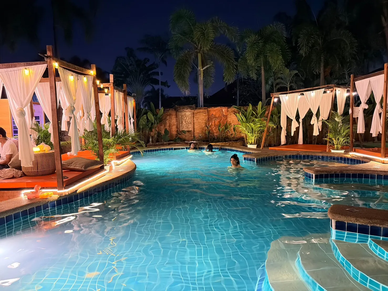 Dewata Wellness Sauna outdoor pool illuminated at night with tropical palms
